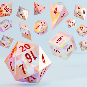 Può includere: Un set di dadi a 12 facce, 20 facce, 10 facce, 8 facce, 6 facce e 4 facce con finiture iridescenti, multicolori e traslucide. I dadi hanno numeri rossi.