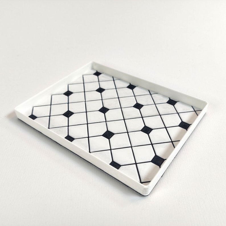 May include: A white rectangular tray with a black and white geometric pattern. The pattern is made up of small squares and diamonds.