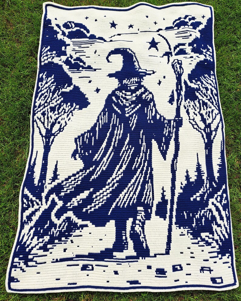 May include: A crocheted blanket featuring a wizard in a dark blue and white design. The wizard is depicted with a staff, hat, and cloak, set against a forest and starry sky backdrop. The blanket is rectangular with a white border.