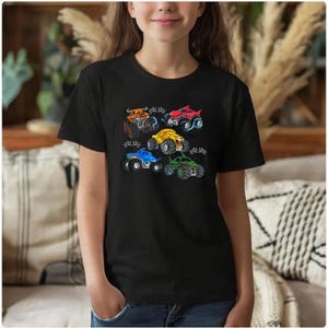 Puede incluir: Camiseta negra con dise&ntilde;os de monster trucks coloridos. Los camiones son de varios colores, incluyendo naranja, rojo, amarillo, azul y verde, cada uno con detalles &uacute;nicos. El dise&ntilde;o est&aacute; centrado en la camiseta, haci&eacute;ndola divertida.