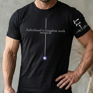 Könnte beinhalten: Schwarzes T-Shirt mit weißem Text "fatherhood is kingdom work" und "PROVERBS 22:6". Eine weiße Linie mit Stern endet auf der Vorderseite. Auf dem rechten Ärmel steht "Liam Noah" und ein Kreuz.