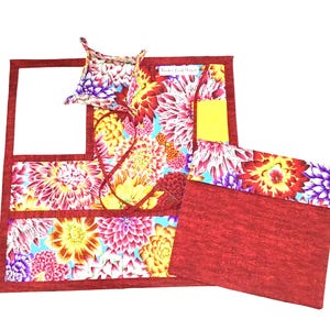 May include: A red fabric organizer with three pockets and a floral print. The organizer has a small, separate, square-shaped pouch with a floral print. The organizer is made of fabric and has a red fabric lining.