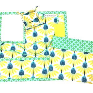 May include: A set of four fabric organizers with a yellow and blue floral pattern. The organizers include a small square tray, a larger rectangular tray, a pouch with a flap, and a long, narrow pouch with a strap. The fabric is green and white with a geometric pattern around the edges.