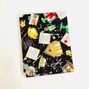 May include: A black fabric with a festive pattern featuring gingerbread houses, candy canes, and recipe cards. The design includes text labels for "Caramels", "Ice Cream", and "Peppermint Stick Candy". The fabric is decorated with colorful sweets.