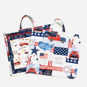 May include: Two red, white, and blue tote bags with patriotic designs. One bag features a red truck, stars, and stripes. The other bag features a red truck, fireworks, and the text "My Home Sweet Home".