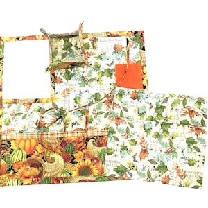 May include: A set of four fabric placemats and a small fabric bowl, all featuring a fall-themed print with leaves, pumpkins, and the text "Fall Days".