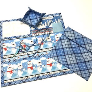 May include: A blue and white fabric sewing kit with a polar bear design. The kit includes a small fabric basket, a pair of scissors, and a piece of fabric. The kit is ideal for storing sewing supplies.