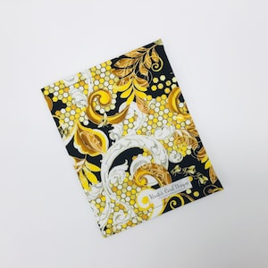 May include: Black fabric with a gold and white pattern of honeycomb, bees, and floral designs. The fabric has the text "Kristi Carol Designs" in the bottom right corner.