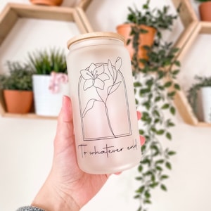 May include: A frosted glass jar with a wooden lid and a black line drawing of a flower. The jar has the text "To whatever end" printed on the front.