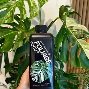 May include: A black bottle of Foliage Focus plant fertilizer with a white monstera leaf graphic. The bottle is labeled with the text "Foliage Focus" and "Grow Technology". The bottle contains 1 quart (946 ml) of fertilizer.