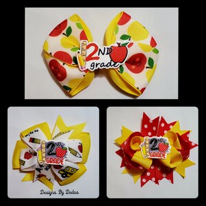 May include: Three handmade hair bows with a school theme. The top bow is white with yellow apples and a yellow border. The center of the bow has a 2nd grade sticker with a red apple and pencil. The other bows have similar designs with red and yellow accents.