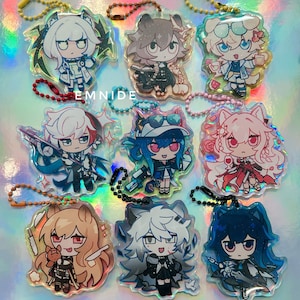 May include: Nine acrylic anime-style character keychains with various designs and colors. Each keychain features a unique character with different outfits and accessories. The keychains are attached to beaded chains and have a holographic background. The text "EMNIDE" is visible.