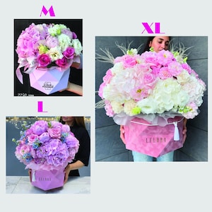May include: Pink, white, and purple floral arrangements in geometric pink boxes. The boxes have the text "LFLORA" on them. The arrangements include roses, hydrangeas, and other flowers. Sizes are labeled M, L, and XL.