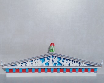 May include: A white model of a Greek temple with a red and blue frieze and a white relief sculpture of figures on the roof. The roof is topped with a green and red sculpture.