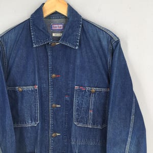 May include: A blue denim jacket with a red stitching detail and a label that reads "Blue Blue" and "Arigato".