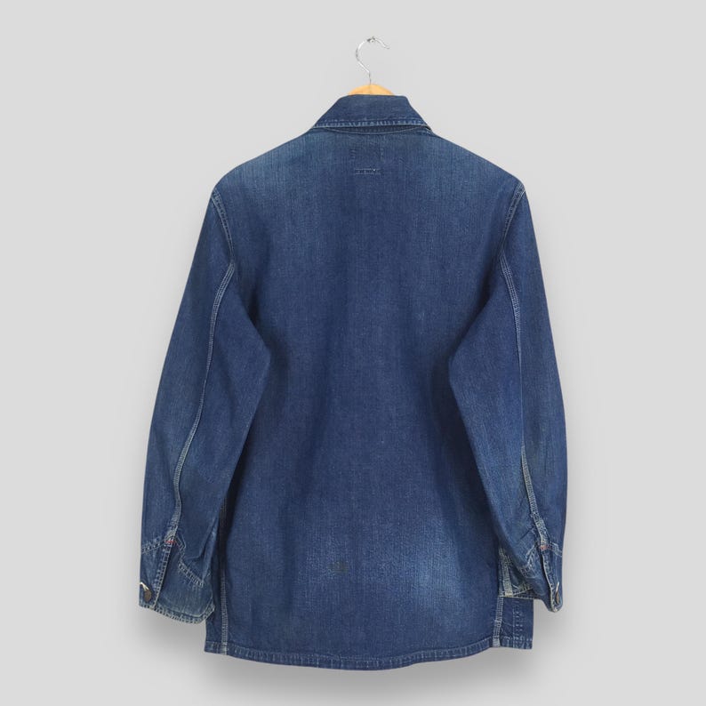 May include: A blue denim work shirt with long sleeves and a button-up front. The shirt is hanging on a wooden hanger.