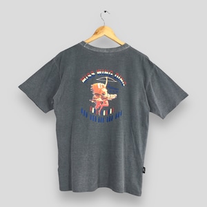 May include: Gray short-sleeve t-shirt with a graphic on the back featuring the text "MISS WING HING" above an illustration of a Native American figure with a bow and arrow. The graphic includes red, white, and blue accents.