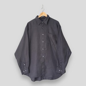 May include: A long-sleeve button-down shirt in a dark charcoal grey colour. The shirt features a classic collar, a single chest pocket on the left side, and buttoned cuffs. It is displayed on a wooden hanger against a plain light grey background.