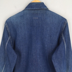 May include: A blue denim long-sleeve shirt with a button-up collar. The shirt has a single back pocket.