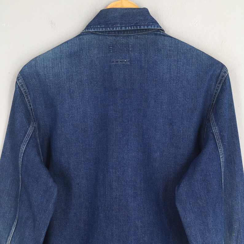 May include: A blue denim long-sleeve shirt with a button-up collar. The shirt has a single back pocket.