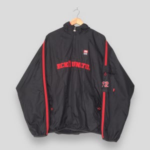 May include: A black quarter-zip windbreaker jacket featuring red vertical stripes down the sleeves and the red text ECKO UNLTD. across the chest. The jacket includes a small red logo on the upper chest and the number 72 on the left sleeve pocket.