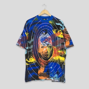 May include: A short-sleeved t-shirt with a vibrant, abstract design. The shirt features a blue crew neck and a colorful pattern with orange, yellow, and blue hues. The design includes concentric circles and a central graphic.