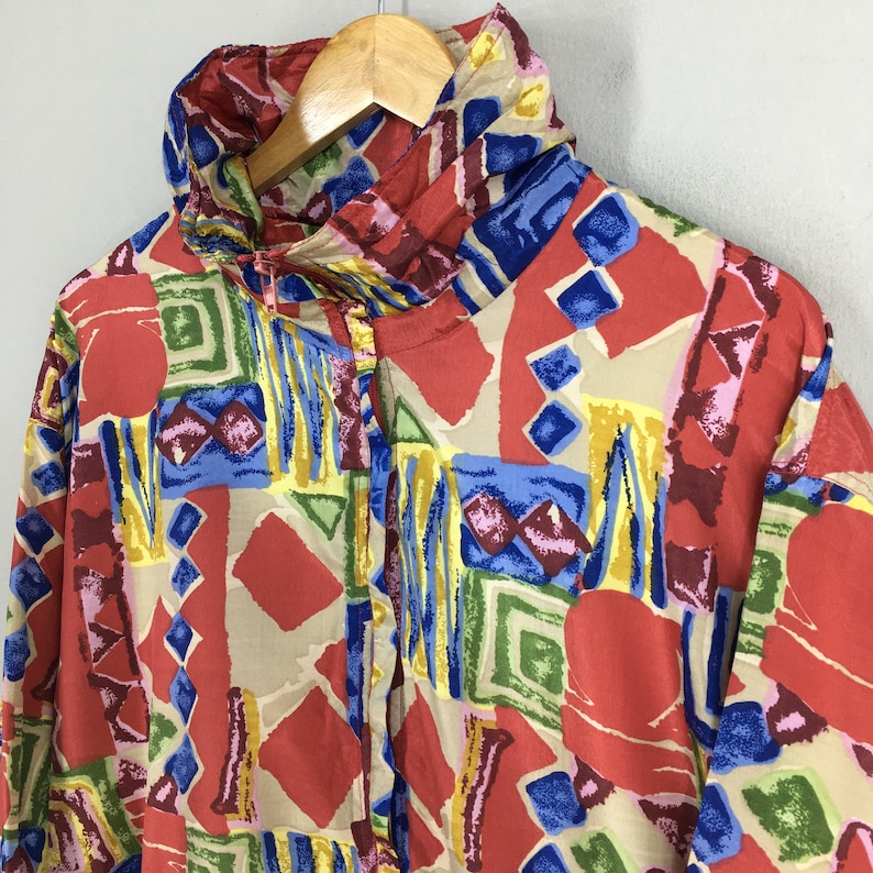 May include: A red, blue, yellow, and green patterned shirt with a high collar and a button-up front.