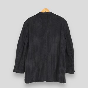 May include: A dark charcoal gray blazer featuring a subtle vertical pinstripe pattern. The garment has long sleeves, a structured collar, and a classic tailored silhouette, presented from a rear-facing perspective against a neutral background.
