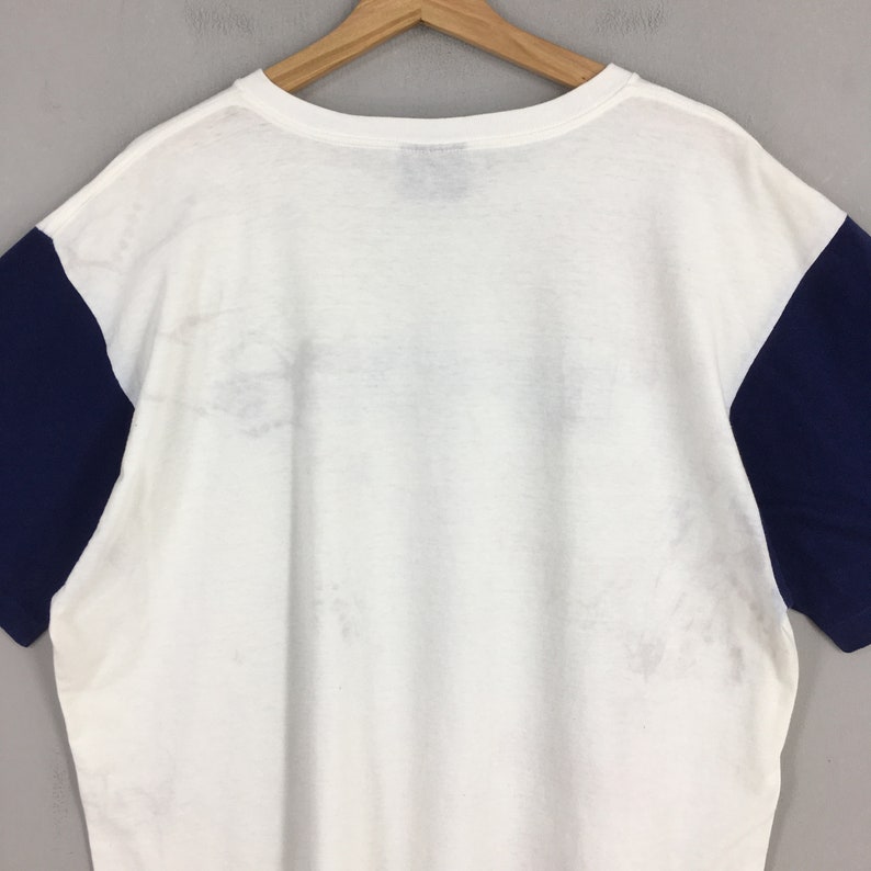 May include: White t-shirt with navy blue sleeves. The shirt has a crew neck and is made of a soft, comfortable fabric.