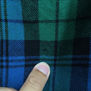 K&ouml;nnte beinhalten: Nahaufnahme eines blauen, gr&uuml;nen und schwarzen karierten Stoffes.