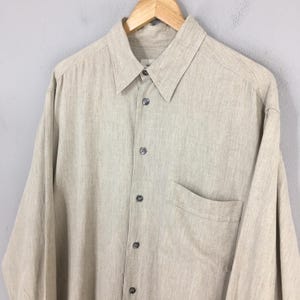 May include: A set of three ceramic mugs with a speckled, matte finish. The mugs are in shades of cream, light gray, and dark gray. Each mug has a simple, minimalist design, perfect for coffee or tea.