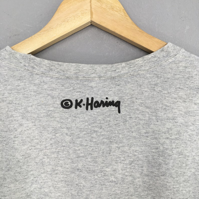 May include: A gray t-shirt with a black print of the text "&copy; K. Haring" on the back.