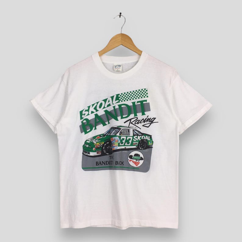 May include: White t-shirt featuring a green and white Skoal Bandit Racing car graphic. The design includes the number 33 and the text "The Bandit Back". The shirt is hanging on a wooden hanger.
