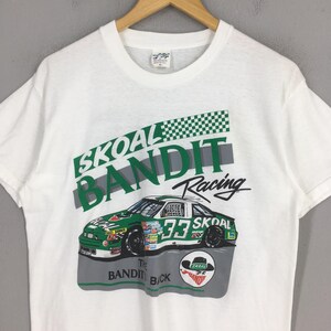 May include: White t-shirt featuring a green and white race car with the number 33, and the words "SKOAL BANDIT Racing". The shirt also has a graphic of a hat and the words "The Bandit Back".