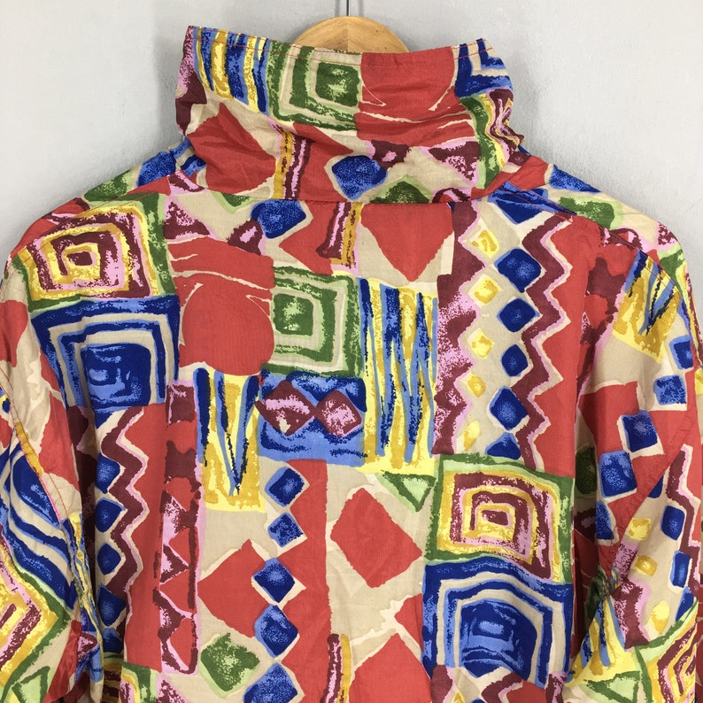 May include: A red, blue, green, yellow, and beige patterned shirt with a high collar. The pattern is abstract and geometric.