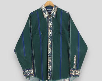 May include: Green long-sleeve button-down shirt with blue and white vertical stripes. The shirt features two chest pockets and decorative patterned accents on the collar, cuffs, and down the front. The shirt is hanging on a wooden hanger.