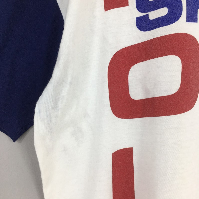 May include: White t-shirt with a blue and red graphic that says "1991" on the front. The shirt has a blue and white color block design on the sleeves.