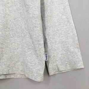 May include: Gray long-sleeve shirt with a small blue tag that says "G/FORE" on it.