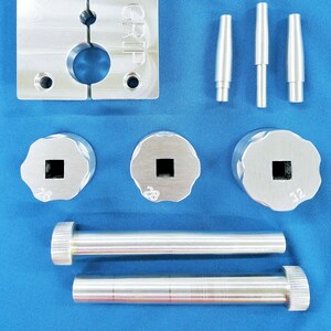 Puede incluir: Un juego de herramientas metálicas para crimpado de conectores de cables. El juego incluye una herramienta de crimpado, tres matrices de diferentes tamaños y dos varillas. La herramienta de crimpado tiene un mango con la palabra "GRIP" grabada. Las matrices están marcadas con los números 26, 28 y 32.