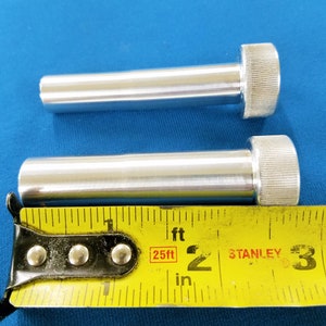 Puede incluir: Dos varillas de metal plateado con extremos roscados, medidas con una cinta métrica Stanley amarilla marcada con 25 pies. Las varillas miden aproximadamente 5 cm de largo.