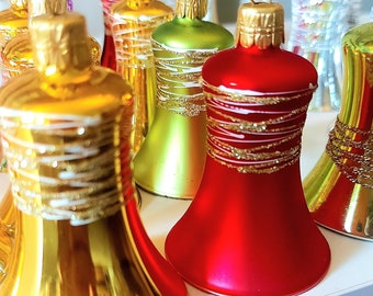 May include: A collection of vintage glass Christmas baubles shaped like bells. The baubles are decorated with gold and white glitter and come in red, green, and gold colours.