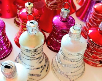 Pode incluir: Uma coleção de enfeites de Natal de vidro coloridos em várias formas. Os enfeites são em tons de vermelho, rosa, dourado e branco, com detalhes prateados e dourados. Alguns têm formato de sino, outros são mais arredondados.