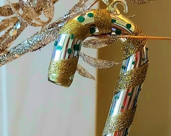 May include: A silver and gold candy cane Christmas ornament with green glitter accents.