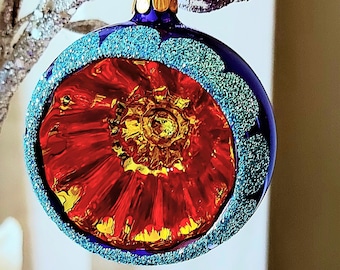 Pode incluir: Um enfeite de Natal de vidro azul com um design de espiral vermelho e dourado. O enfeite tem um acabamento brilhante.