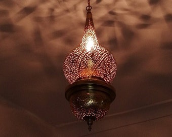 May include: A decorative hanging light fixture with a round, openwork, copper-colored shade. The shade has a teardrop shape and is illuminated by a light bulb inside.