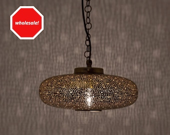 May include: An oval-shaped, antique brass pendant light fixture with a perforated design. The light hangs from a chain and emits a warm glow. The fixture is suspended against a textured, neutral-toned wall.