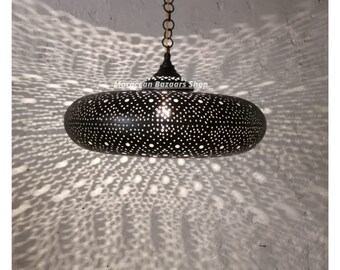 May include: A black metal pendant light with a round, perforated shade. The shade has a starburst pattern and is hanging from a chain.