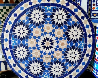 Könnte beinhalten: Eine runde Tischplatte mit marokkanischem Fliesenmuster. Die Fliesen sind blau, weiß und beige und haben ein Sternenmuster. Die Tischplatte hat einen Durchmesser von 76 cm.