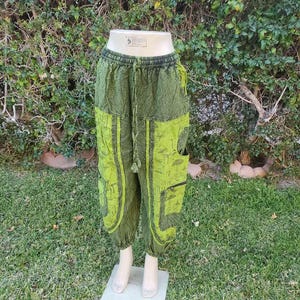 May include: Green printed trousers with a drawstring waist and a pocket on the right side. The trousers have a mushroom design.