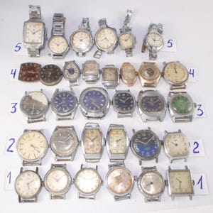May include: A collection of vintage wristwatches with various face shapes and band styles. The watches feature silver, gold, and brown tones, with some displaying Roman numerals and others Arabic numerals. The collection includes both round and rectangular watch faces.